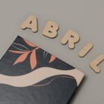Wooden letters spelling Abril on a flat surface with abstract art cover beneath, creating a modern aesthetic.